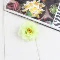 Light green artificial flower hair clip detail with soft fabric petals and yellow center. - Light Green