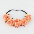 Artificial rose floral headband detail shot showing peach velvet flowers and black elastic band - Orange