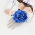 Detail view of Halloween skeleton hand hair clip featuring blue rose for party costume accessory. - Sapphire Blue