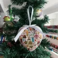 Detailaufnahme eines herzförmigen Weihnachtsschmucks mit bunten tropischen Motiven am Baum. - Stil 6-00000 Täglich