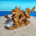 Closeup detail view of golden Chinese dragon tea pet figurine holding crystal ball on sand. - Chinese Dragon Style B
