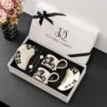 Gedetailleerd overzicht van luxe keramische koffieservies met kopjes en schotels in geschenkdoos. - Kersenbloesem