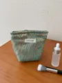 Detailed shot of a luxury jacquard cosmetic bag featuring a golden wave pattern. - S / Light Green Ocean