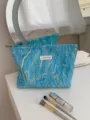 Detailed view of embossed blue makeup bag with gold wave pattern and storage capacity. - L / Blue