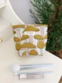 Close-up detail of the canvas cosmetic makeup bag featuring cute yellow mushroom embroidery. - Yellow, Small