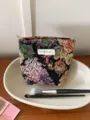 Detailed view of a vintage floral embroidered cosmetic bag with zipper and custom label. - S / Black Purple Floral
