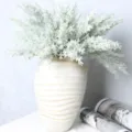 Detailed close-up shot of artificial pine branches and foliage placed in a rustic ceramic vase. - Flocked Green Cypress Leaf