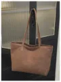Brown tote bag detail view, showing the durable shoulder straps and textured surface material. - Brown No Pendant