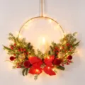 Détail de couronne de Noël en fer, poinsettia rouge et or, boules floquées et guirlande lumineuse. - 86132+Lumière+Bougie