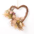 Detail close-up of heart-shaped rattan wreath with artificial roses and burlap bow decor. - Purple 76791