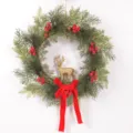 Christmas wreath detail showcasing artificial pine branches, red berries, and glitter deer. - Golden Deer Style