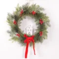 Christmas wreath with pine branches, red berries, white house ornament and red velvet bow. - Wooden House Style