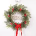Christmas wreath detail featuring artificial pine branches, red berries and velvet bow. - Letter Plate Style