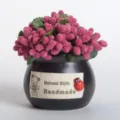 Close-up of a mini potted artificial pink berry plant with a black ceramic pot and fabric label. - Black Mini Tank Dark Red Glass Bead