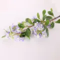 Primo piano dettagliato di un ramo di fiori artificiali viola con foglie verdi per casa. - Blu Viola con Foglie