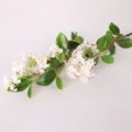 Primo piano dettagliato di un ramo di fiori artificiali con fiori rosa e foglie verdi. - Rosa con Foglie