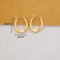 Primer plano detallado de pendientes de aro ovalados dorados con altura de 26mm y anchura de 20mm. - Pendientes Ovalados Retorcidos / Dorado