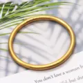 Primer plano de un brazalete macizo de latón dorado mate, con textura fina y curva elegante. - Dorado Mate
