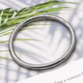 Detalle en primer plano de pulsera de metal liso, diseño de joyería plateada minimalista. - Acero Pulido