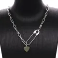 Vista detallada del collar con dije de corazón y imperdible geométrico de acero titanio. - Estilo 2