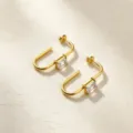 Primer plano detallado de pendientes en U de acero inoxidable chapado en oro con circonita. - Blanco
