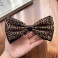 Detailed close-up of the retro leopard print bow hair clip featuring a cute metallic dog charm. - Dog Charm Bow Style / Yellow Leopard