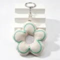 Nahaufnahme des niedlichen bestickten Plüsch-Blumen-Schlüsselanhängers mit Ring. - Gebrochenes Weiß