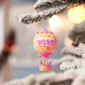 Primo piano del ciondolo a mongolfiera 2025 su ramo di pino innevato, decorazione festiva. - 8cm