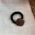 Primer plano detallado de una goma de pelo elástica negra con adorno cuadrado de acetato. - Coletero Cuadrado Acetato - Café Claro