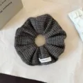 Gedetailleerde opname van donkerbruin gebreide haarband met zachte wolstructuur en label. - Lichtkoffie
