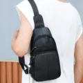 Detail shot showing a black genuine leather sling bag worn comfortably across the back. - Black