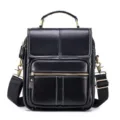 Black leather shoulder bag detail, vertical design with metal hardware and zipper pocket. - Black