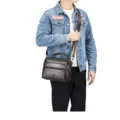 Close-up view of dark brown leather messenger bag, multi-zipper design, durable strap. - Coffee