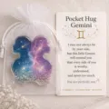 Detail view of Gemini pocket hug acrylic token with constellation card and white organza bag. - Gemini
