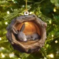 Close-up detail of the cute sleeping donkey inside wooden tree hollow Christmas ornament hanging. - Tree Hole Donkey