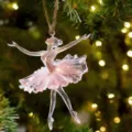 Gros plan d'un ornement de ballerine en acrylique rose transparent, pose gracieuse sur l'arbre. - 8cm / Style 6