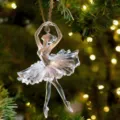 Gros plan d'un ornement de ballerine en acrylique transparent suspendu au sapin de Noël lumineux. - 8cm / Style 10