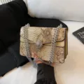 Κομψή τσάντα ώμου με αλυσίδα και μοτίβο φιδιού με μεταλλικό κούμπωμα κεφαλής λιονταριού. - Χρυσό