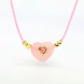 Nahaufnahme einer rosa Herz-Kristall-Halskette mit goldenen Akzenten und Wachskordel. - 03#