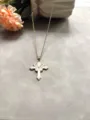 Gros plan détaillé d'un collier croix doré chic avec un joli pendentif papillon rose. - Rose