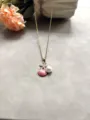 Gros plan sur le collier chaîne dorée avec un pendentif coquillage rose et perle. - Pêche