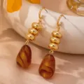 Boucles d'oreilles pendantes style vintage français en résine ambrée et perles dorées détail. - Style Spirale Long Trois Perles d'Or Vintage Français (JMX-ER9857)