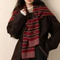 Detail view of a striped wool knit scarf, stylish layered winter fashion accessory. - Black Red