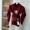 Detailed view of burgundy knit jacquard shawl layered over white sequin top with wool tag. - Pure Wool Jacquard Shawl - Red / One Size