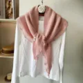 Pink knit triangle scarf detail, cozy winter shawl draped over white long sleeve top close up. - Pink