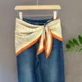 Blue denim jeans styled with a beige and orange paisley scarf tied at the waist for women. - 20#