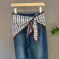 Blue denim jeans paired with a multi-color striped triangle scarf stylishly tied at the waist. - 7#