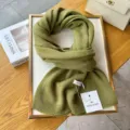 Detailed close-up shot of a cozy green knitted wool scarf styled neatly on a board. - Grass Green