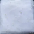 White tulle fabric with scattered pearls, perfect for bridal wedding veils and DIY crafts. - White
