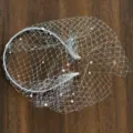 Detail view of the elegant white bridal birdcage veil headband sparkling with delicate rhinestones for party. - White